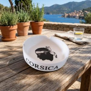 Cendrier Corsica en verre blanc motif Tête de Maure posé sur une table en bois
