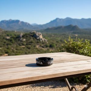 Cendrier Corsica en verre noir motif Tête de Maure posé sur une table en bois