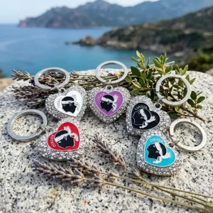 Porte-clés souvenir de Corse : cœur en métal argenté orné de strass, avec le symbole de la tête de Maure et le texte "Corsica" au centre. Anneau d'attache gravé.