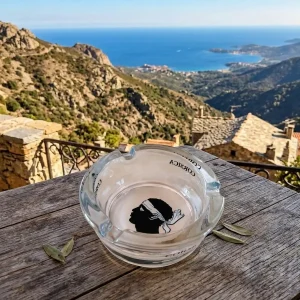 Cendrier Corsica transparent verre posé sur une table de terrasse