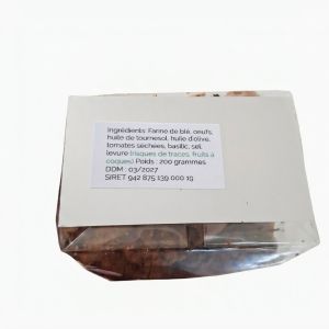 Sachet de canistrelli salés au basilic présentés sur une table en bois avec tomates séchées et basilic