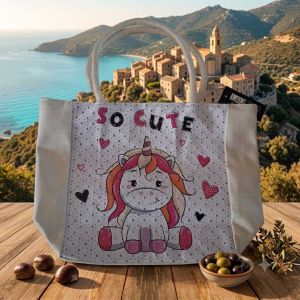 Sac cabas enfant en toile illustré d'une licorne rose avec la mention So Cute, posé sur une table en Corse