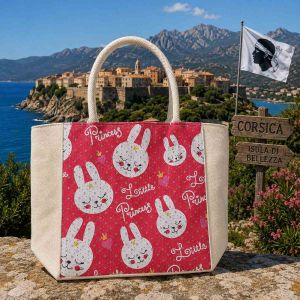 Sac cabas enfant en toile avec imprimé rose fuchsia, têtes de lapins blanches et inscription Little Princess devant la citadelle d'Algajola.