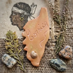 Magnet Corse en argile fait main posé sur de la pierre avec coquillages, bois flotté et symbole de la tête de maure