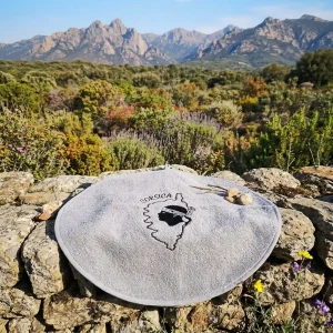 Torchon rond en éponge gris Casa Mea brodé Corsica et Tête de Maure sur muret en pierre